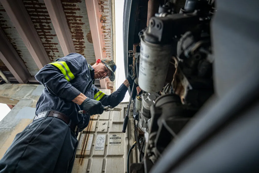 view from the ground of a truck mechanic working on truck refrigeration system