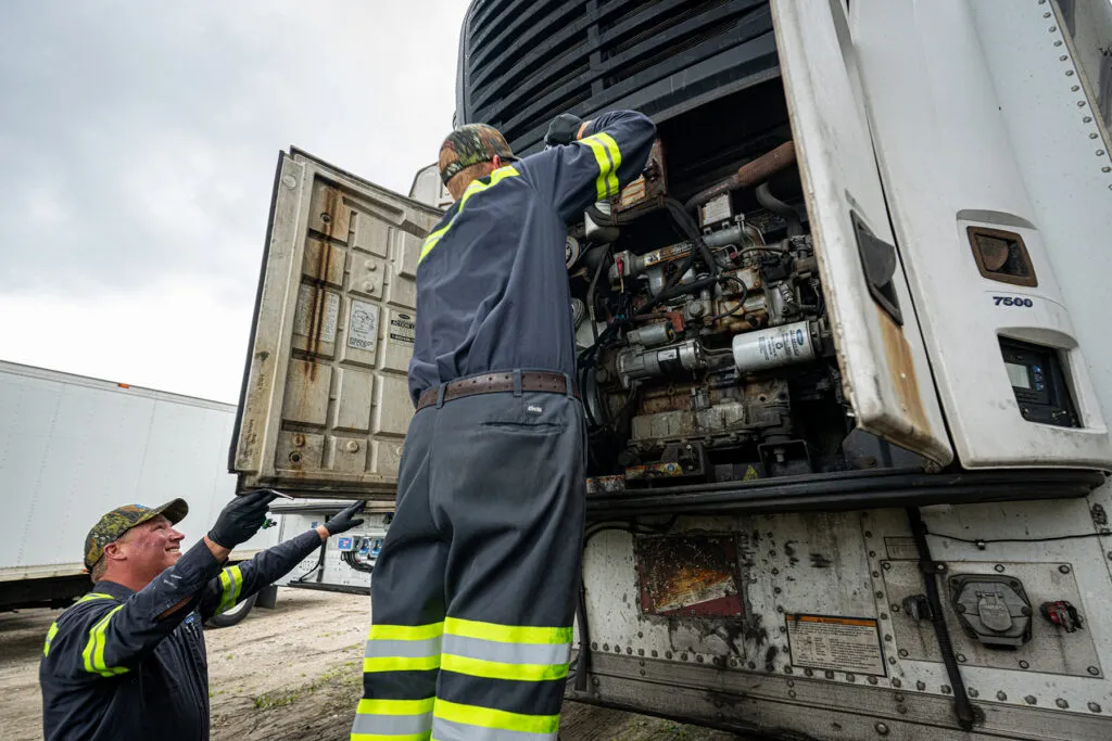 Two Multimarine technicians servicing a Carrier unit attached to a trailer.