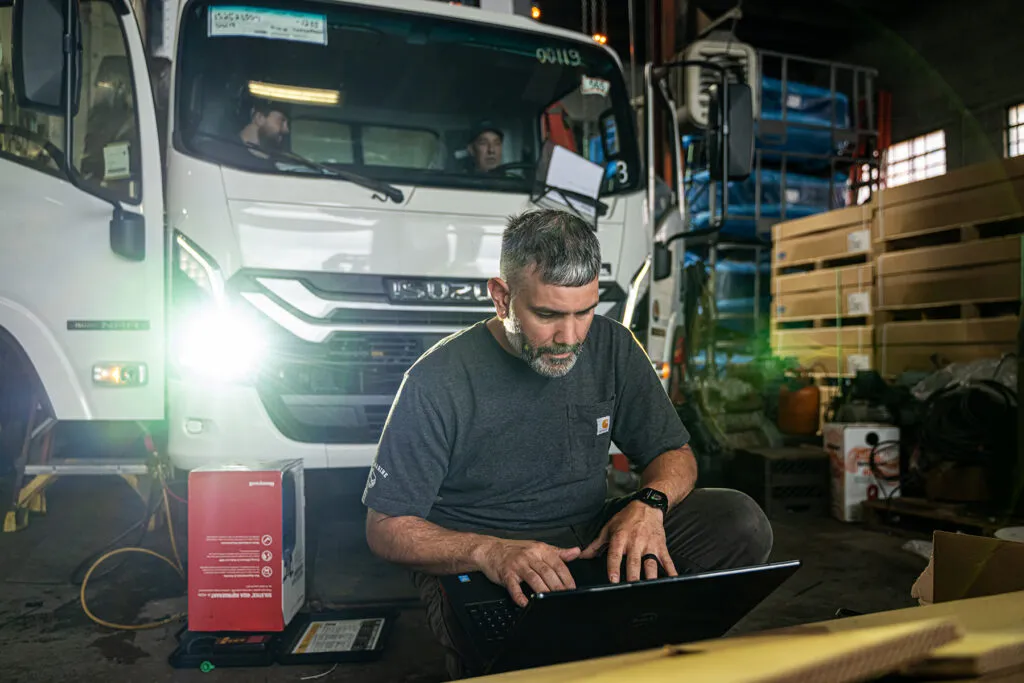 testing refrigerated truck systems with a laptop in a repair shop
